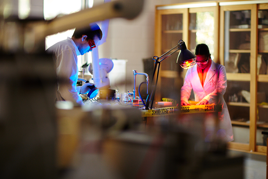Two people in white lab coats working a crime scene science lab